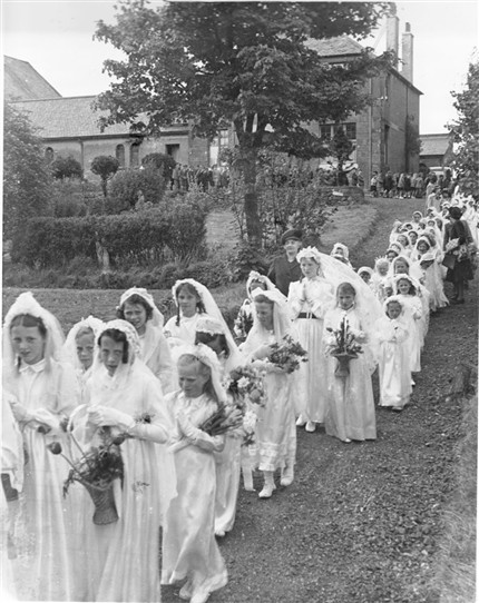 Photo:First communicants.  In the background the chapel (left), and Presbytery [the priest's house] (right).